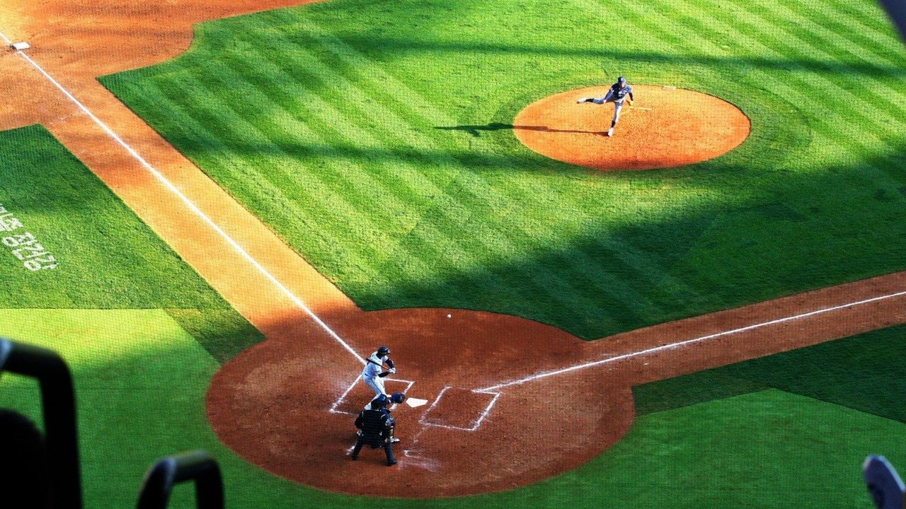 Baseball pitcher throwing from the raised mound toward batter at home plate during a live game.